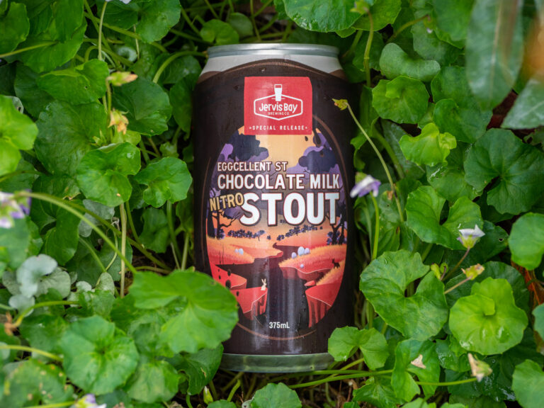 Brown Can of Eggcellent St Chocloate milk nitro stoud, with cartoon setting of chocolate river, placed in clover